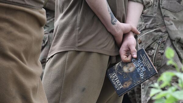 جنودي أوكراني أسير يحمل كتابا  في أحد السجون بجمهورية دونباس الشعبية - سبوتنيك عربي