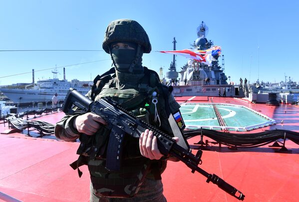 جندي من مشاة البحرية الروسية يحمل مدفع رشاش على ظهر طراد صواريخ بطرس الأكبر الذي يعمل بالطاقة النووية في سيفيرومورسك. 1 يونيو 2022 - سبوتنيك عربي