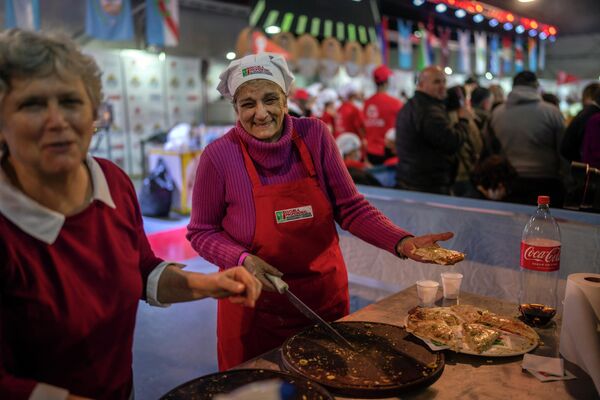 متطوعون يبتسمون أثناء توزيع شرائح البيتزا، التي صنعها خبراء البيتزا، أثناء حضور &quot;بطولة البيتزا الأرجنتينية&quot; في بوينس آيرس، الأرجنتين، 7 يونيو 2022. - سبوتنيك عربي