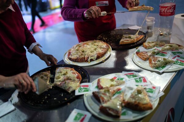 متطوعون يوزعون على الحضور قطع البيتزا، التي أعدها خبراء البيتزا خلال &quot;بطولة البيتزا الأرجنتينية&quot; في بوينس آيرس، الأرجنتين، 7 يونيو 2022. - سبوتنيك عربي