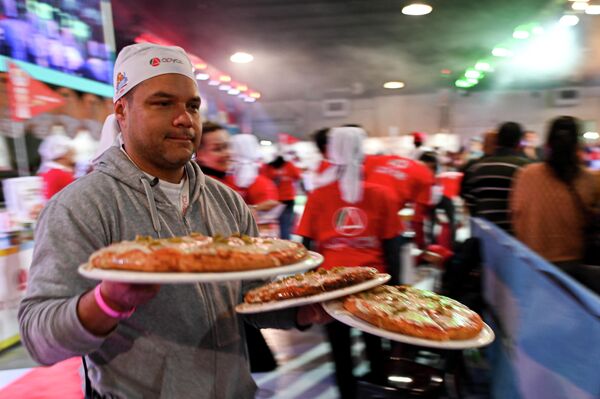 رجل يقوم بتوزيع البيتزا على الحضور في &quot;بطولة البيتزا الأرجنتينية&quot; العاشرة في بوينس آيرس، الأرجنتين 7 يونيو 2022. - سبوتنيك عربي