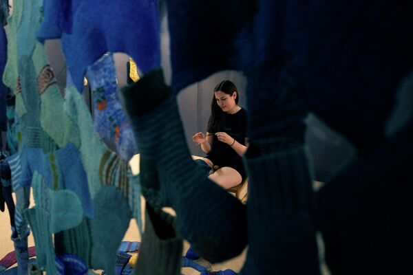 امرأة، من أكاديمية لاتفيا للفن، تقوم بإصلاح الجوارب، تم اختيار الجوارب كإشارة مجازية لأي منتج من منتجات القرن الـ21 التي تدعم الاستهلاك اليومي، في إطار معرض ديزاين فير (Design Fair) في ميلانو، إيطاليا، 7 يونيو 2022. - سبوتنيك عربي