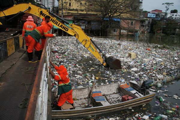 عمال المدينة يزيلون القمامة العائمة على نهر نيغرو ، الذي يرتفع منسوب المياه بسبب الأمطار ، في ماناوس، ولاية أمازوناس ، البرازيل ، تتم إزالة حوالي 35 طنًا من القمامة يوميًا من المياه، البرازيل، 6 يونيو عام 2022. - سبوتنيك عربي
