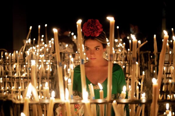 فتاة تضيء شمعة في حرم لـ عذراء روسيو  بقرية إل روسيو في ألمونتي بإسبانيا، خلال موسم الحج السنوي، يوم السبت 4 يونيو 2022 - سبوتنيك عربي