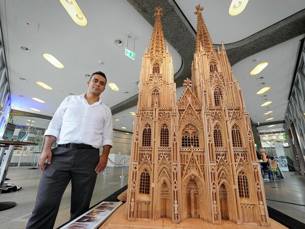 فاضل الخضر من سوريا يقف بجانب النموذج الخشبي لكاتيدرائية كولونيا التراثية الذي تم عرضه في دومفوروم في كولون بألمانيا، الاثنين 20 يونيو 2022 - سبوتنيك عربي