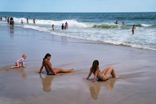 رواد الشاطئ يستمتعون بركوب الأمواج في سميث بوينت كاونتي بارك، وهو شاطئ لونغ آيلاند حيث قام سمكة قرش بتدوير منقذ قبل 10 أيام، في شيرلي، نيويورك، 15 يوليو 2022 - سبوتنيك عربي