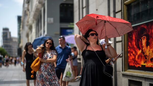امرأة تحمل مظلة للاحتماء من أشعة الشمس خلال يوم مشمس حار في مدريد، إسبانيا، 18 يوليو 2022. - سبوتنيك عربي
