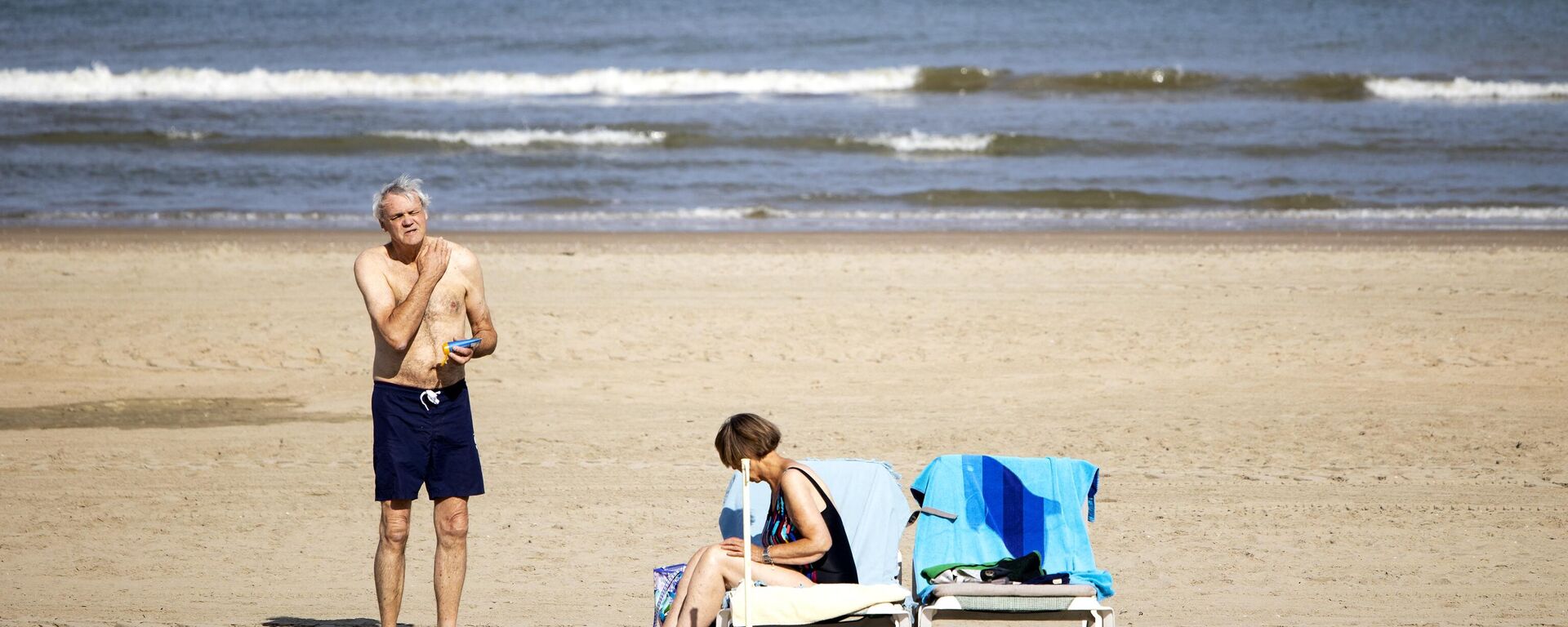 رجل يضع كريم واقي الشمس على الشاطئ في زاندفورت في 18 يوليو 2022. - سبوتنيك عربي, 1920, 21.07.2022
