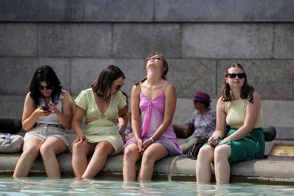 مجموعة من النساء تضع أقدامهن في مياه نافورة ترافالغار سكوير في وسط لندن في 18 يوليو 2022 حيث تشهد البلاد موجة حرارة شديدة. - سبوتنيك عربي
