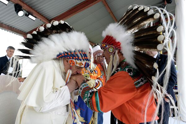 هذه الصورة التي تم التقاطها ونشرها في 25 يوليو 2022 من قبل المكتب الصحفي للفاتيكان تظهر البابا فرانسيس (على اليسار) يرتدي غطاء رأس قدمه له قادة السكان الأصليين في موسكوا بارك في ماسكواسيس، جنوب إدمونتون، غرب كندا، في 25 يوليو 2022.البابا فرانسيس يزور كندا للحصول على فرصة للاعتذار شخصيًا للناجين من السكان الأصليين من الانتهاكات التي ارتكبت على مدى عقود في مدارس داخلية تديرها الكنيسة الكاثوليكية. - سبوتنيك عربي