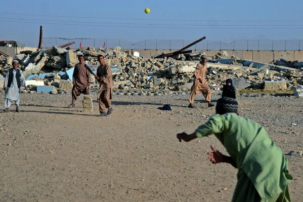 الأولاد يلعبون الكريكيت أمام مدرسة تضررت أثناء الصراع بين &quot;طالبان&quot; والحكومة الأفغانية الحاكمة السابقة، في قندهار في 12 مايو 2022. - سبوتنيك عربي