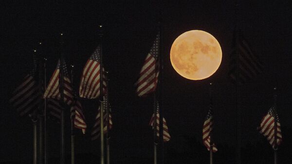 يرتفع القمر خلف أعلام الولايات المتحدة عند قاعدة نصب واشنطن التذكاري في 11 أغسطس 2022 في واشنطن العاصمة. ما يسمى بقمر الحفش هو القمر العملاق الرابع والأخير لعام 2022 - سبوتنيك عربي