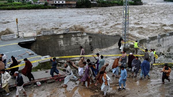 يتجمع الناس أمام طريق تضررت به مياه الفيضانات بعد هطول أمطار موسمية غزيرة في منطقة ماديان في شمال وادي سوات في باكستان في 27 أغسطس 2022. - - سبوتنيك عربي