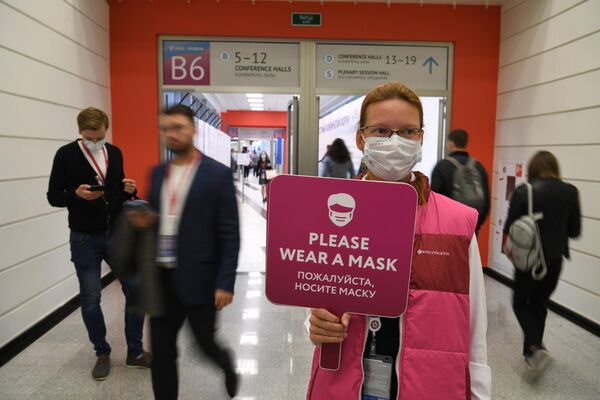 فتاة تحمل لافتة توصية بارتداء الكمامة في المنتدى الاقتصادي الشرقي العالمي في فلاديفوستوك، روسيا 5 سبتمبر 2022 - سبوتنيك عربي