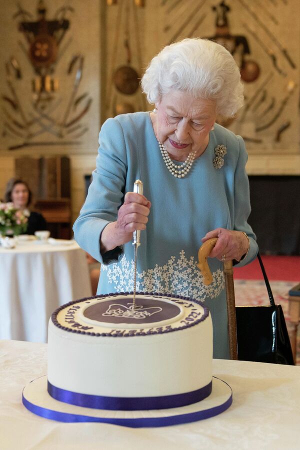 ملكة بريطانيا إليزابيث الثانية تقطع كعكة للاحتفال ببدء اليوبيل البلاتيني، في ساندرينجهام هاوس، مقر إقامتها في نورفولك، في ساندرينجهام، إنجلترا، 5 فبراير 2022. - سبوتنيك عربي