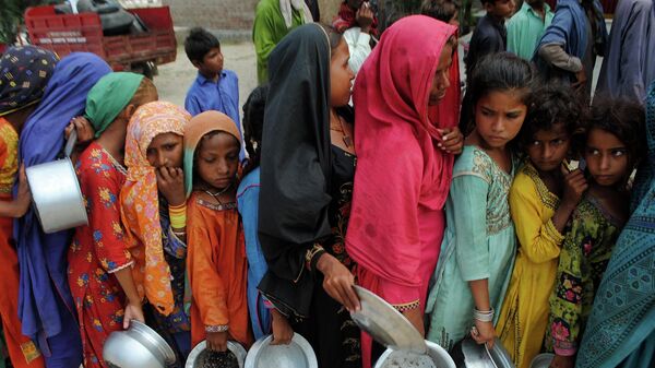 الناس من المناطق المتضررة من الفيضانات ينتظرون تلقي الغذاء الذي وزعه صندوق الرعاية الاجتماعية سايلاني، في لال باغ، مقاطعة السند، باكستان، 13 سبتمبر 2022. - سبوتنيك عربي