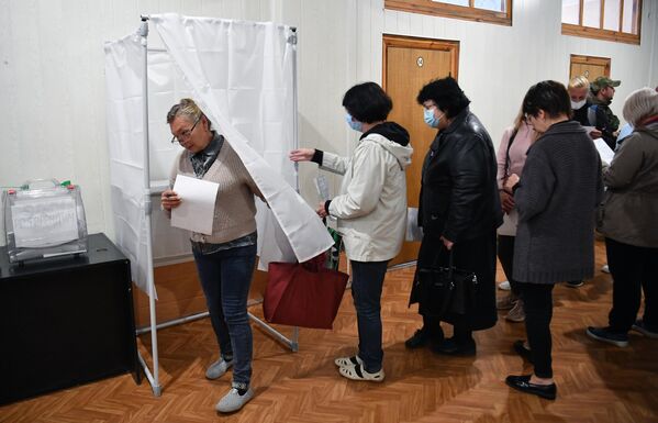 يصوت الناس في استفتاء على انضمام مقاطعة زابوروجيه إلى روسيا في مركز اقتراع في مؤسسة ميليتوبول، 23 سبتمبر 2022 - سبوتنيك عربي