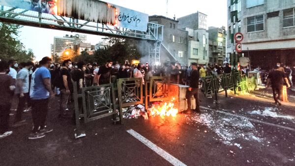 متظاهريون إيرانيين يحرقون صندوق قمامة في العاصمة طهران خلال احتجاج لمحساء أميني، بعد أيام من وفاتها في حجز الشرطة،  إيران في 21 سبتمبر 2022 - سبوتنيك عربي