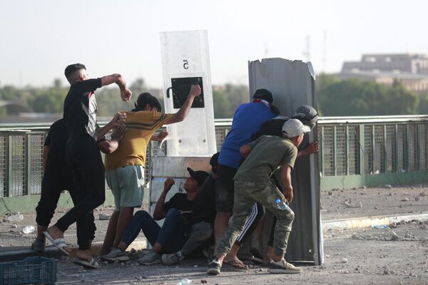 متظاهرون مناهضون للحكومة يرشقون الحجارة على قوات الأمن العراقية خلال مظاهرة في ساحة التحرير في بغداد، العراق، 28 سبتمبر 2022. - سبوتنيك عربي