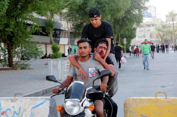 متظاهرون عراقيون مناهضون للحكومة يحملون جريحًا خلال مظاهرة في ساحة التحرير في بغداد، العراق، 28 سبتمبر  2022. - سبوتنيك عربي