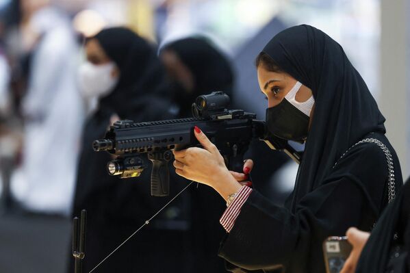 زائرة تتفقد بندقية خلال معرض أبوظبي الدولي للصيد والفروسية (ADIHEX) في العاصمة الإماراتية، 1 أكتوبر 2022. - سبوتنيك عربي