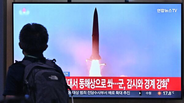 رجل أمام شاشة تلفزيونية تظهر بثًا إخباريًا لتجربة صاروخ لـ كوريا الشمالية 29 سبتمبر 2022 - سبوتنيك عربي