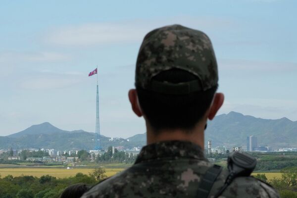 علم كوريا الشمالية يرفرف بينما يقف جندي من الجيش الكوري الجنوبي في حراسة قرى بانمونجوم الحدودية في باجو، كوريا الجنوبية، 4 أكتوبر 2022. - سبوتنيك عربي