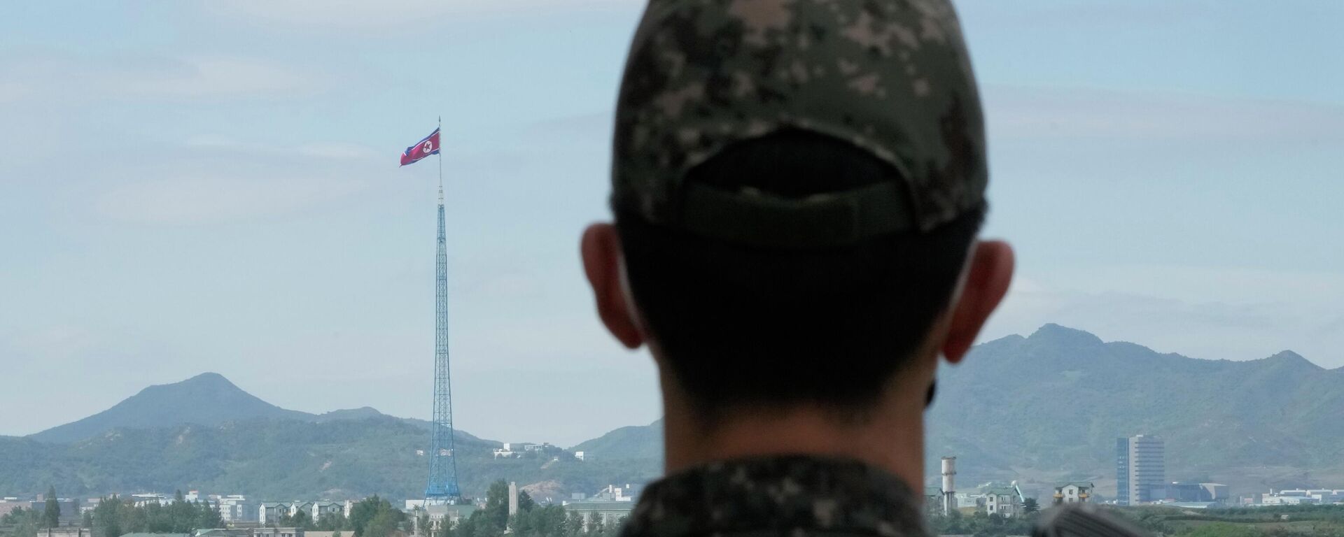 علم كوريا الشمالية يرفرف في مهب الريح بينما يقف جندي من الجيش الكوري الجنوبي في حراسة قرى بانمونجوم الحدودية في باجو، كوريا الجنوبية، 4 أكتوبر 2022. - سبوتنيك عربي, 1920, 02.11.2022