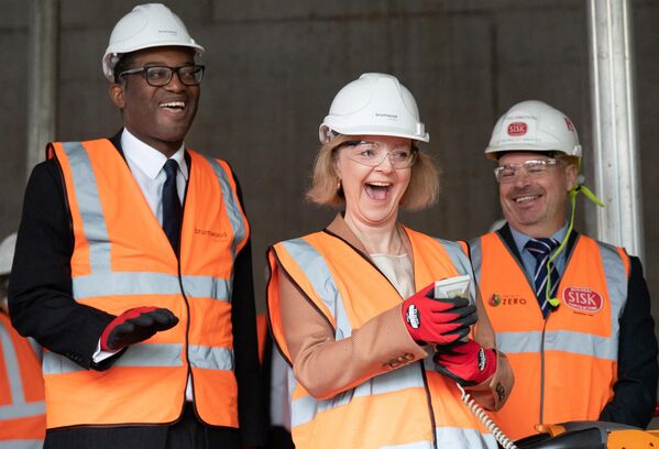 رئيس الوزراء البريطاني ليز تراس (وسط) ووزير الخزانة البريطاني كواسي كوارتنغ (يسار) يرتديان قبعات صلبة وسترات عالية الرؤية، يزوران موقع بناء لحرم جامعي للابتكار الطبي في برمنغهام، وسط إنجلترا، في 4 أكتوبر 2022. - سبوتنيك عربي