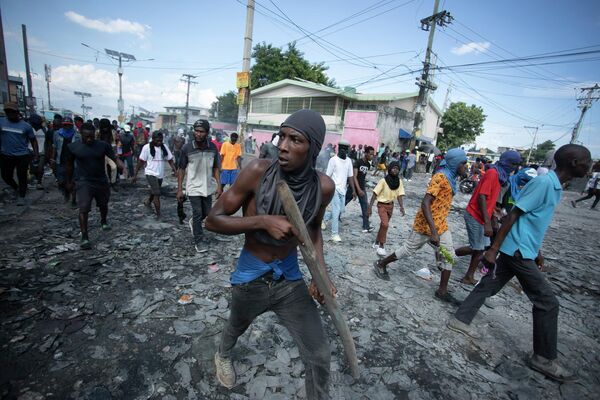 متظاهر يحمل قطعة من الخشب تحاكي سلاحًا خلال مظاهرة تطالب باستقالة رئيس الوزراء أرييل هنري، في منطقة بيتيون فيل في بورت أو برنس، هايتي، يوم 3 أكتوبر 2022. - سبوتنيك عربي