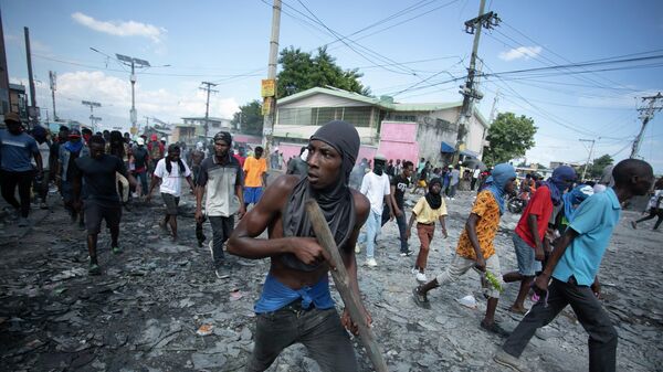 Протестующий несет кусок дерева, имитирующий оружие, во время акции протеста с требованием отставки премьер-министра Ариэля Генри в Гаити - سبوتنيك عربي