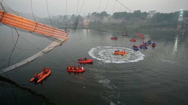 Спасатели на лодках ведут поиск в реке Мачу рядом с вантовым подвесным мостом, который обрушился в городе Морби западного штата Гуджарат, Индия - سبوتنيك عربي