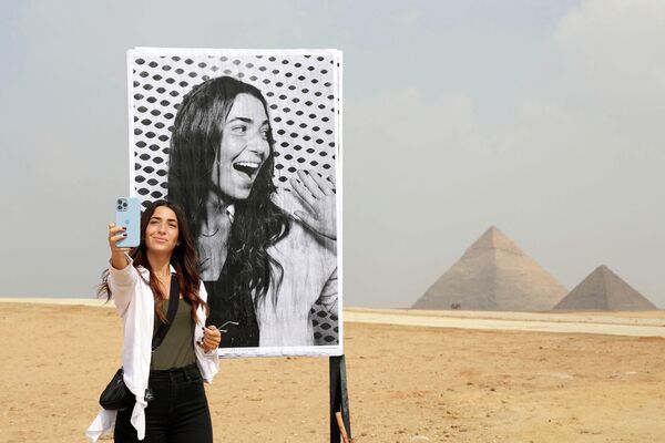 امرأة مصرية تلتقط صورة سيلفي أمام صورتها المطبوعة من غرفة تصوير على هضبة الأهرام في الجيزة، مصر 27 أكتوبر 2022. - سبوتنيك عربي