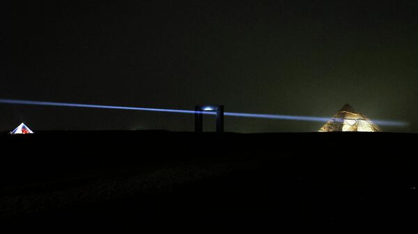 تركيب فني للفنان الإيطالي إميليو فيرو، أُطلق عليه اسم بوابة النور، يقع على هضبة الأهرامات، حيث يظهر التثبيت للفنان الفرنسي الملقب بـ جيزة إنسايد أوت في الخلفية (يسار) في الجيزة في 29 أكتوبر 2022. - سبوتنيك عربي