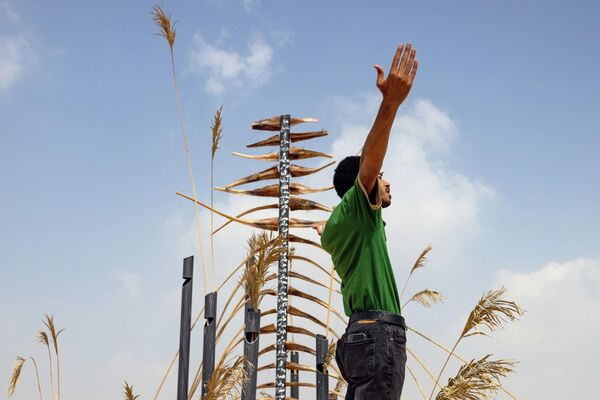محمد الفرج يقف بالقرب من التركيب الفني الخاص به، الملقب بـ حراس الريح على هضبة الأهرامات في الجيزة في مصر، 27 أكتوبر 2022 - سبوتنيك عربي