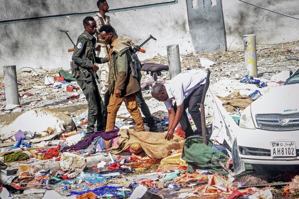 رجال الإنقاذ وقوات الأمن يقفون إلى جانب جثة في مكان هجوم مزدوج بسيارة مفخخة في مقديشو، الصومال، 29 أكتوبر 2022. - سبوتنيك عربي