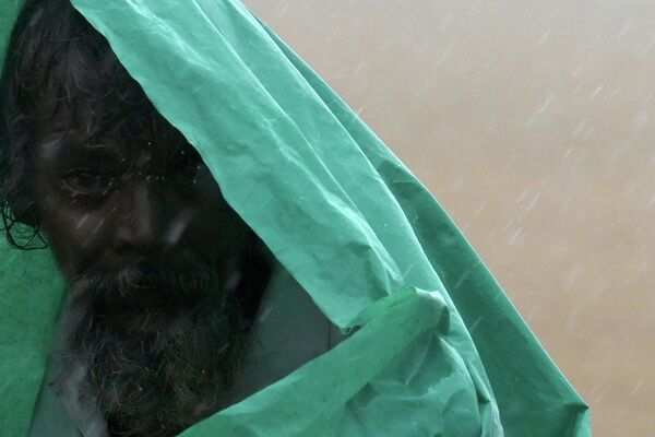 رجل يغطي نفسه بغطاء بلاستيكي أثناء هطول أمطار موسمية غزيرة في تشيناي في الهند، 1 نوفمبر 2022. - سبوتنيك عربي