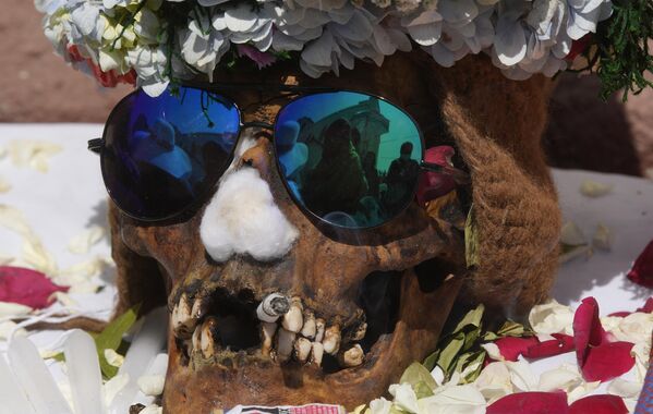 جمجمة بشرية مزخرفة موضوعة على الشاشة ليباركها كاهن خلال مهرجان ناتيتاس (Natitas) السنوي، وهو تقليد بمناسبة نهاية عطلة جميع القديسين الكاثوليكية، في المقبرة العامة في لاباز، بوليفيا، 8 نوفمبر 2022 - سبوتنيك عربي