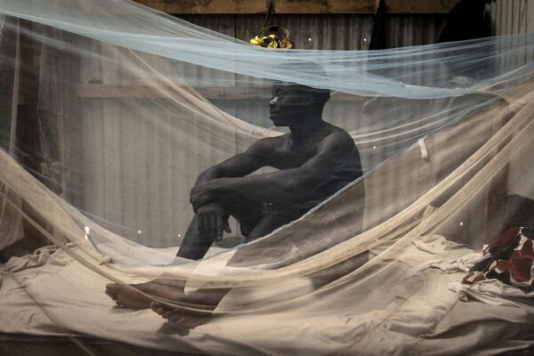 عامل بناء يجلس على سريره في معسكر في ديامنياديو، في سيراليون 8 نوفمبر 2022 - سبوتنيك عربي