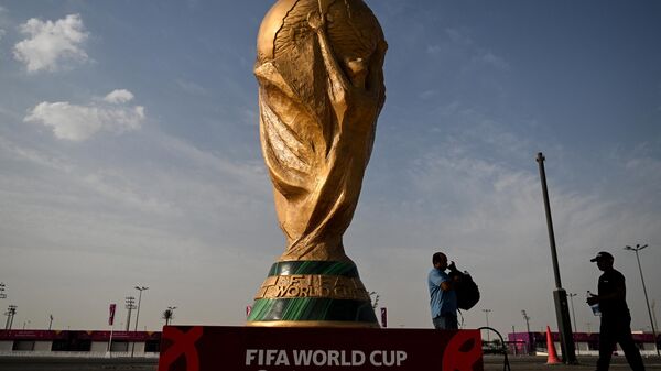 رجال يمشون أمام نسخة طبق الأصل من كأس العالم لكرة القدم خارج استاد أحمد بن علي في الريان في 12 نوفمبر 2022 ، قبل بطولة كأس العالم لكرة القدم قطر 2022. - سبوتنيك عربي