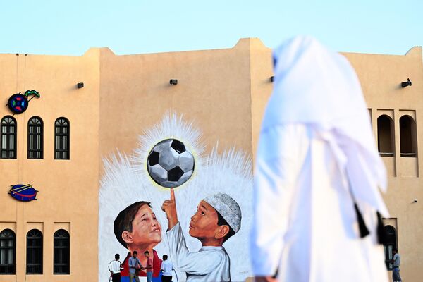 أشخاص يسيرون أمام لوحة جدارية في الدوحة في 8 نوفمبر 2022، قبل بطولة كأس العالم لكرة القدم قطر 2022. - سبوتنيك عربي