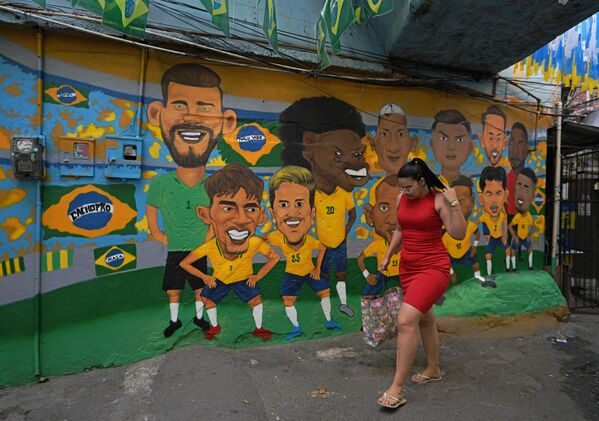 امرأة تمر بجانب لوحة جدارية تصور فريق كرة القدم البرازيلي لكأس العالم في  روسينها فافيلا في ريو دي جانيرو، البرازيل، 23 نوفمبر 2022. - سبوتنيك عربي