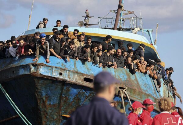 المهاجرون ينظرون من قارب صيد يرسو في ميناء باليوكورا في جنوب شرق جزيرة كريت، اليونان، بعد وصوله، 22 نوفمبر 2022 - سبوتنيك عربي