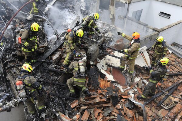 رجال الإطفاء يعملون في موقع تحطم طائرة صغيرة سقطت فوق منازل في منطقة سكنية في ميديلين، كولومبيا، 21 نوفمبر  2022. - سبوتنيك عربي