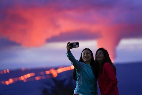الامرأتان تلتقطان صورة سيلفي على خلفية الحمم التي اندلعت من بركان ماونا لوا في هاواي، بالقرب من هيلو، هاواي.30 نوفمبر 2022  - سبوتنيك عربي