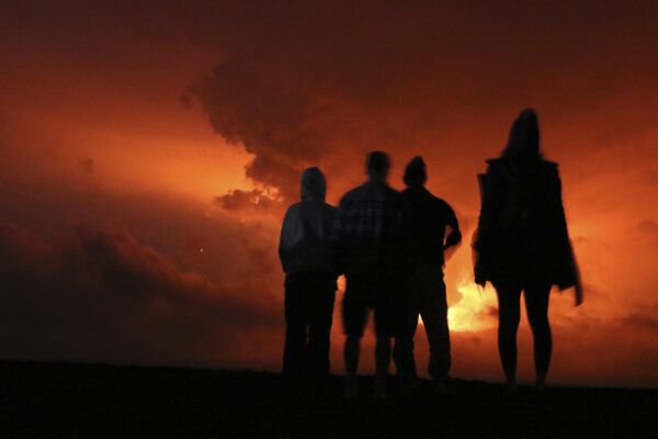 الناس يشاهدون الوهج من الحمم البركانية التي تنفجر من بركان ماونا لوا في هاواي، في هيلو، 28 نوفمبر 2022. - سبوتنيك عربي