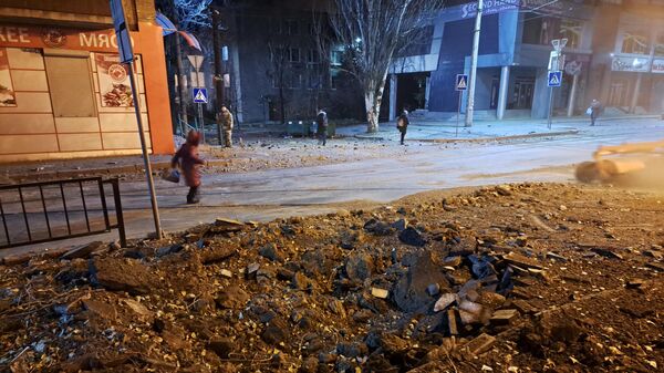 Люди проходят мимо воронки от взрыва после ночного обстрела Донецка - سبوتنيك عربي