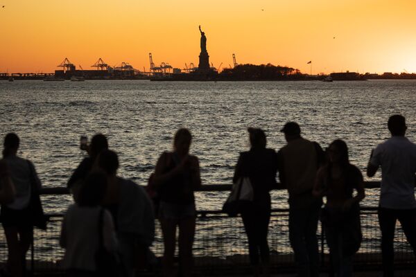 الناس يشاهدون غروب الشمس خلف تمثال الحرية في 7 نوفمبر 2022 في نيويورك.  - سبوتنيك عربي