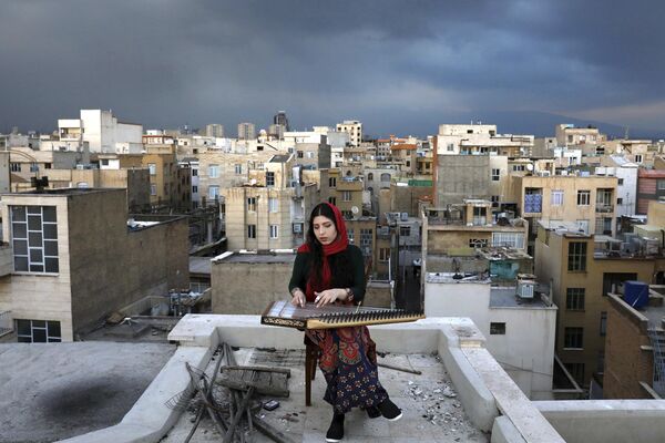 فتاة إيرانية تعزف على سطح منزلها أثناء العزلة الذاتية الإلزامية بسبب تفشي فيروس كورونا الجديد في طهران، إيران - سبوتنيك عربي