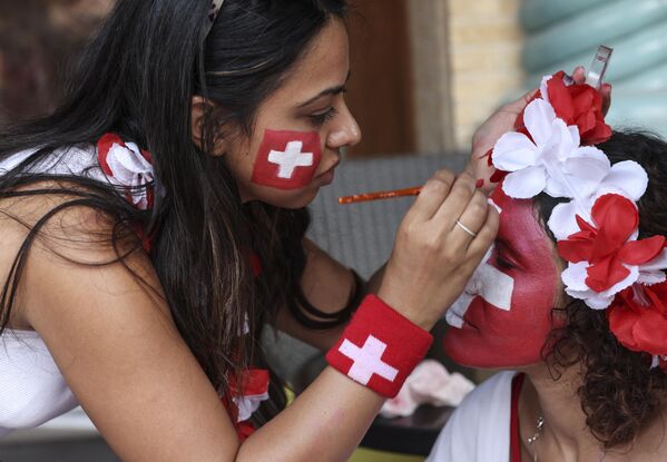 مشجعة سويسرا ترسم على وجه صديقتها في سوق واقف بالدوحة، قبل مباراة كأس العالم لكرة القدم قطر 2022 بين البرازيل وسويسرا، في 28 نوفمبر 2022. - سبوتنيك عربي